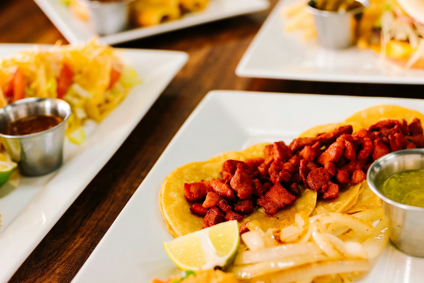 Platos de tacos servidos con limón y salsa en una mesa.