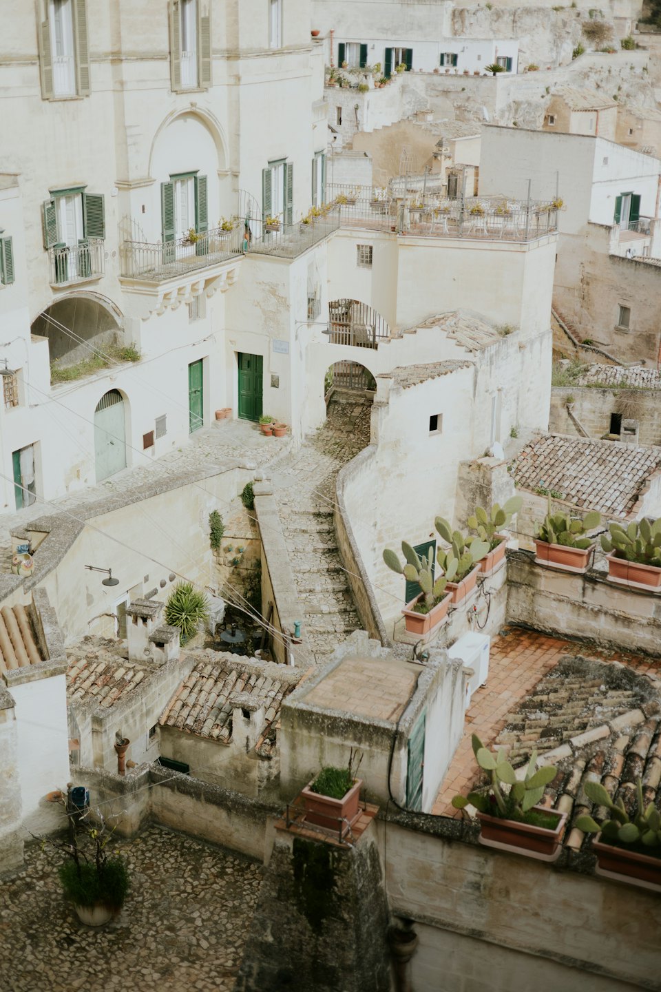 Edificios históricos de pueblo con contraventanas verdes y escaleras de adoquín.